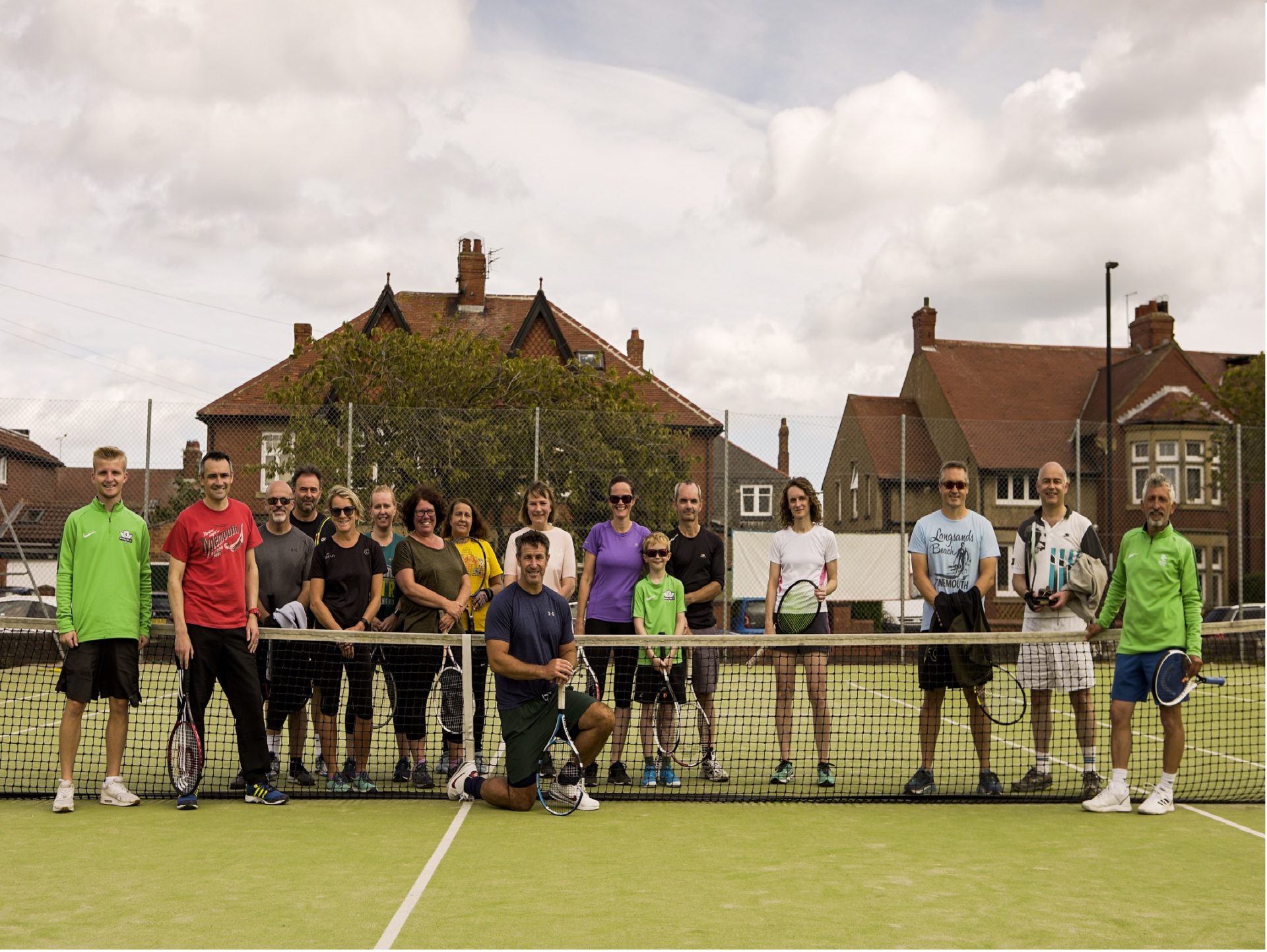 Adult tennis coaching group at the net
